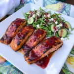 Raspberry Salmon with Herb Salad served with glossy berry glaze and fresh herbs