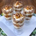 Four homemade Apple Pie Yogurt Parfaits layered with cinnamon apples and Greek yogurt and granola