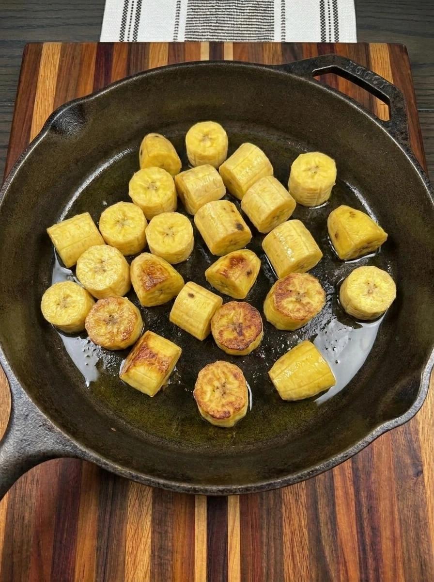 Golden plantain pieces browning in a skillet