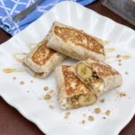 Banana Wrap with Honey and Granola cut open on a white plate