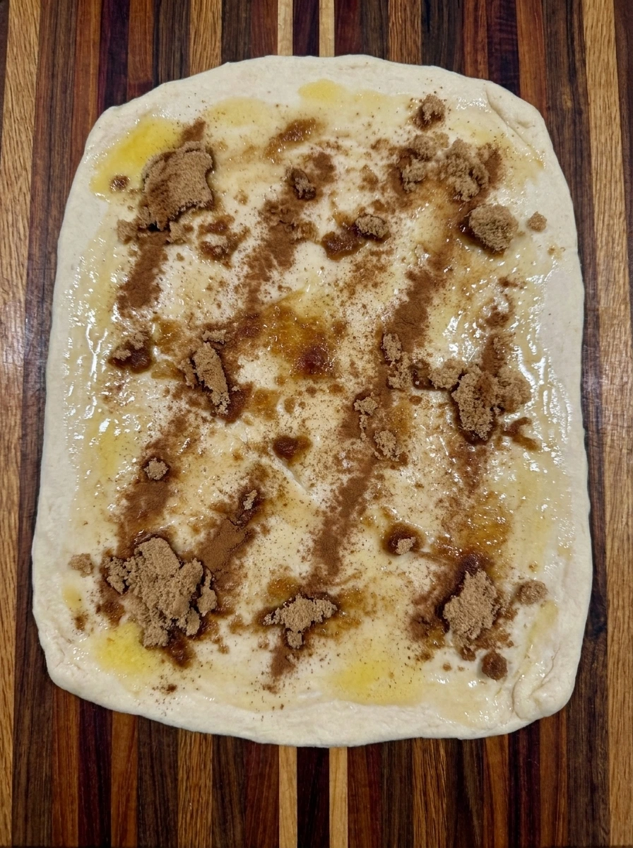 Cinnamon sugar filling spread over dough for Caramel Pecan Cinnamon Rolls