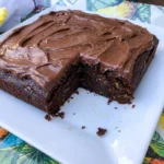 Moist Chocolate Zucchini Cake with thick chocolate frosting and one slice removed