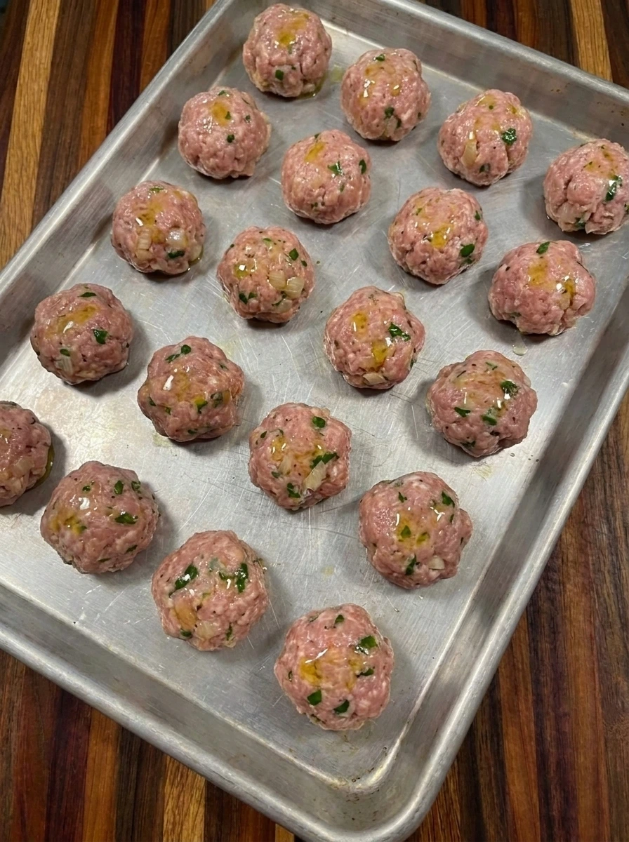 Twenty shaped raw Cranberry Meatballs on a sheet pan
