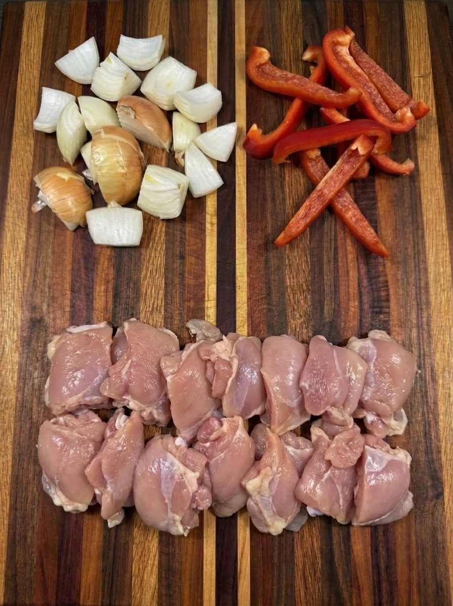 Cut chicken thighs with chopped onion and sliced red pepper for coconut chicken curry