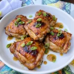 Crockpot Honey Garlic Chicken coated in glossy sauce with green onions and sesame seeds