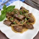 Crockpot Steak Bites coated in garlic butter sauce with onions and parsley