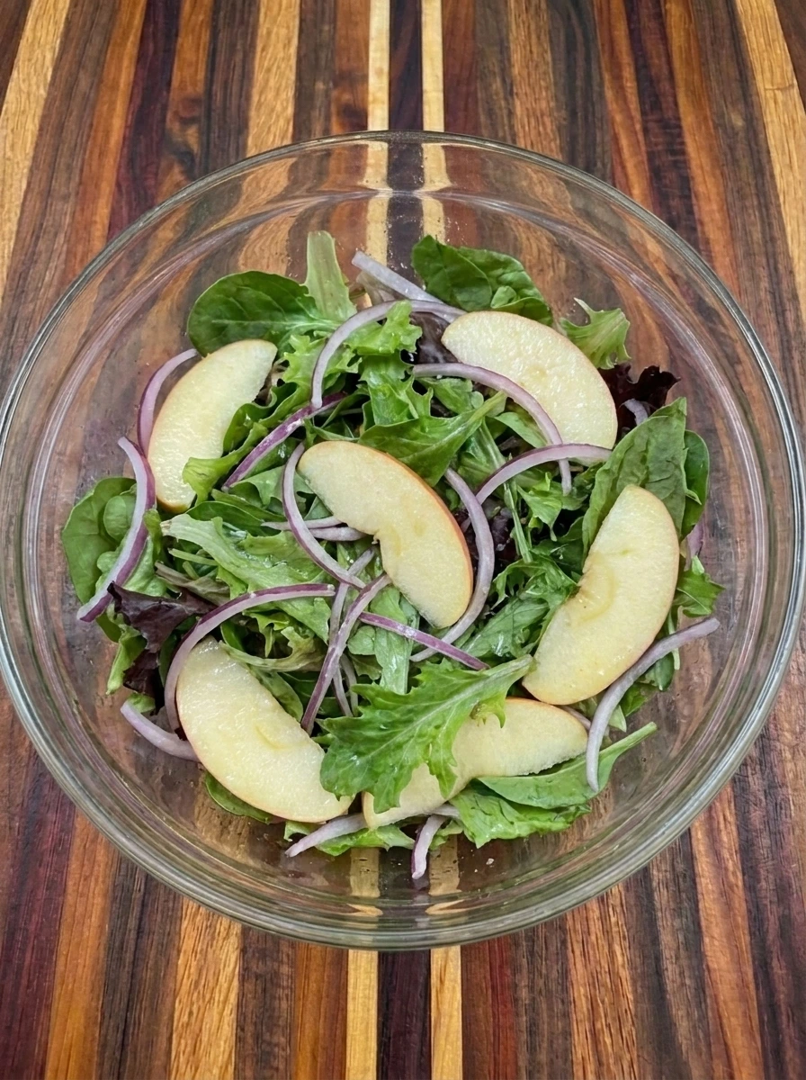 Greens folded with apples and red onion for Pecan Apple Salad