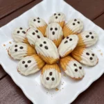 Halloween Ghost Madeleines coated with white chocolate and decorated with dark chocolate faces