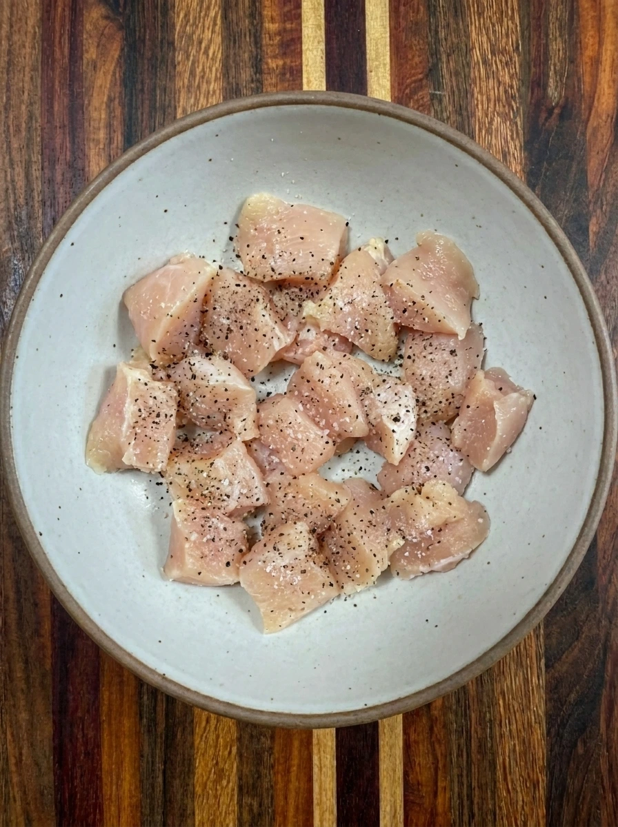 Two chicken breasts cut into seasoned bite size pieces