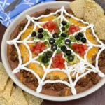 Spiderweb Taco Dip topped with sour cream web and taco toppings