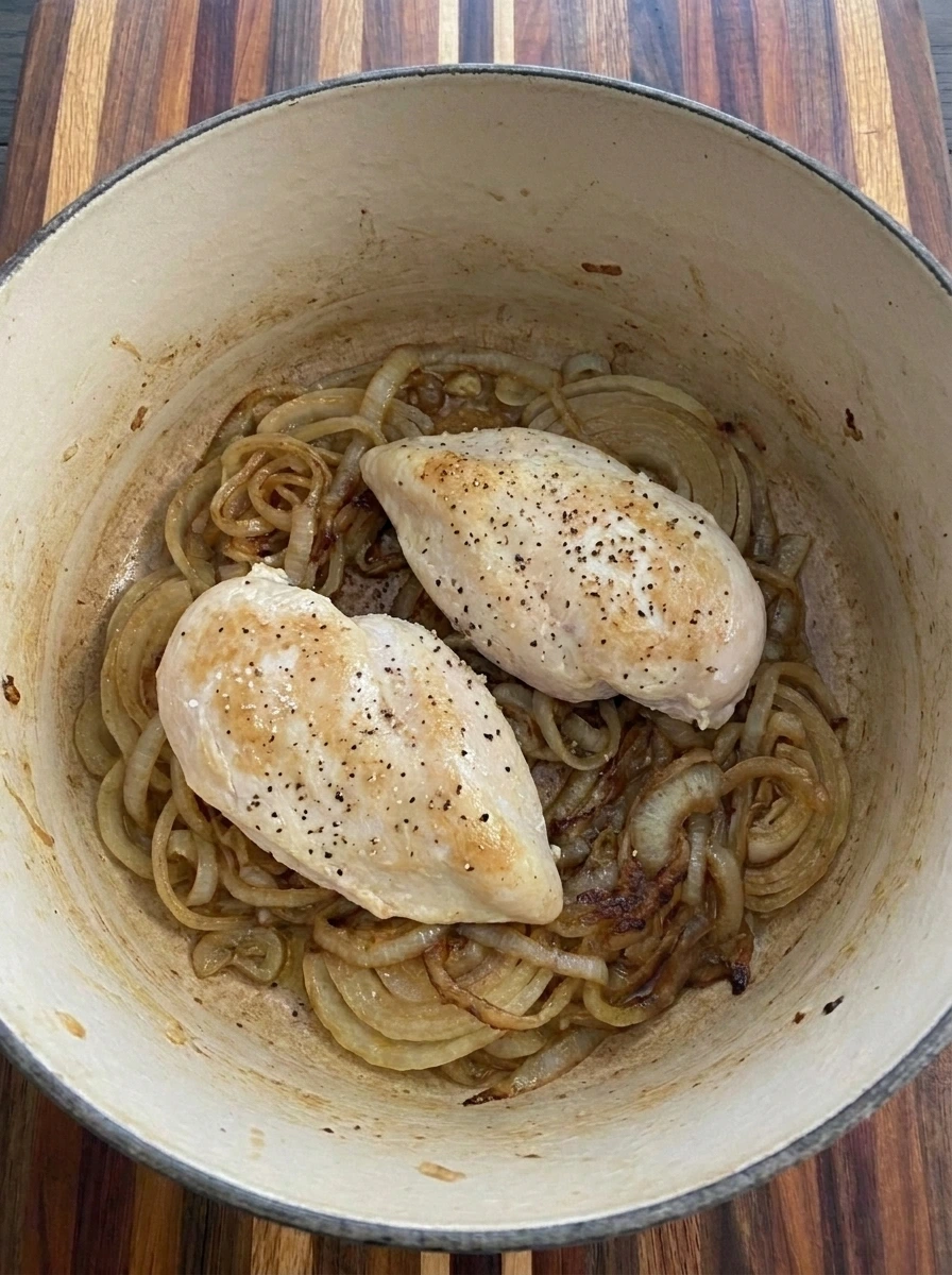 Two chicken breasts browning with caramelized onions for French Onion Chicken Soup