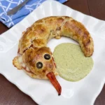 Golden Snakewich with Venom Sauce shaped like a snake with olive eyes and a red pepper tongue