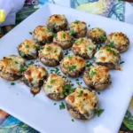 Golden baked Boursin-Stuffed Mushrooms filled with creamy garlic herb cheese on a white serving plate