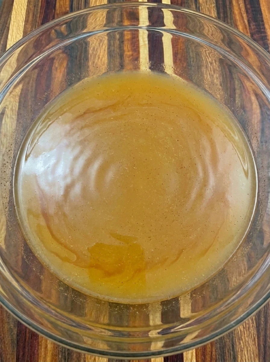 Apple cider mixed with caramel sauce cinnamon and lemon juice in a glass bowl