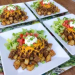 Loaded Potato Taco Bowl with crispy roasted potatoes and taco beef topped with melted cheddar and lettuce and tomatoes
