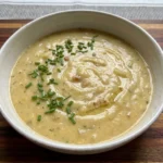Creamy Roasted Garlic Potato Soup in a ceramic bowl topped with fresh green chives