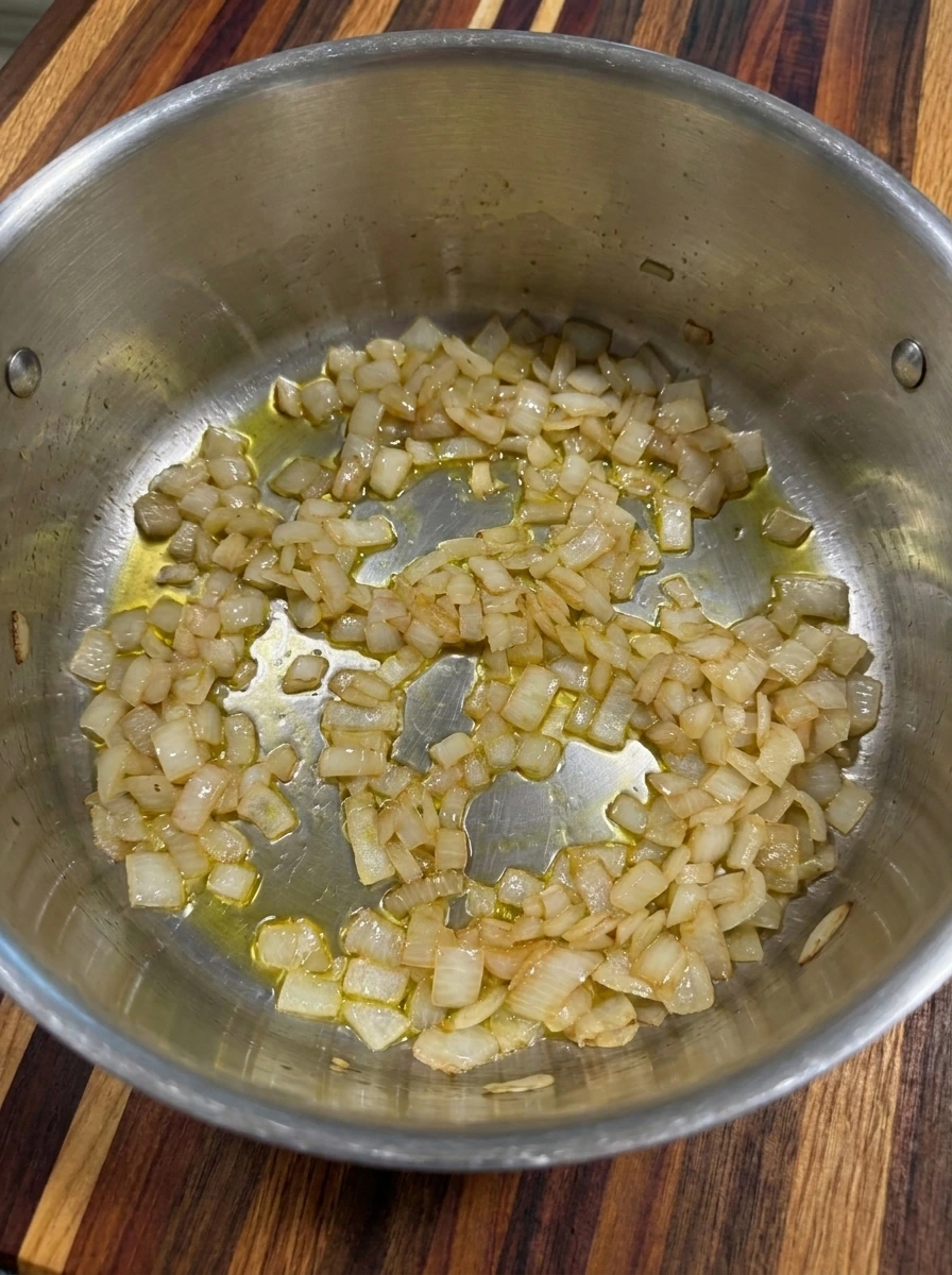 Soft translucent diced onions sautéed in olive oil inside a soup pot