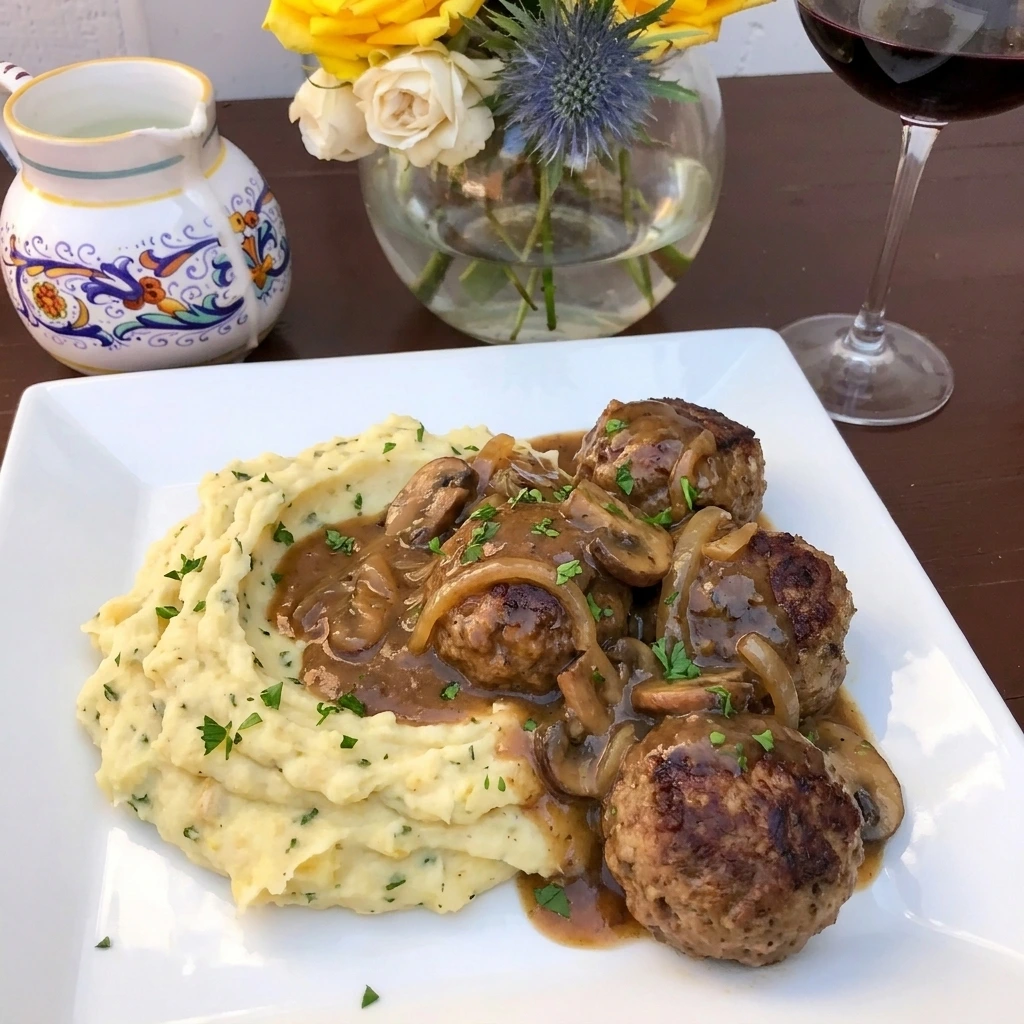 Four Salisbury steak meatballs with garlic herb mashed potatoes and mushroom gravy