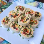 Finished Taco Tortilla Roll-Ups with creamy taco filling and cheddar and colorful vegetables